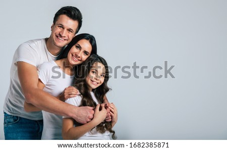 Our life! Beautiful excited and the funny family team is posing in a white t-shirt while they isolated on white background in studio.