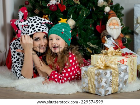 Mother and daughter in festive home clothes under the Christmas tree smiling and talking