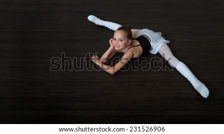 A little adorable young girl doing stretching exercises on the floor. Ballet,  gymnastics, free callisthenics.