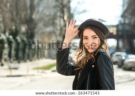 Beautiful brunette girl in casual clothes walking around the city. Fashion and city style. Facial expression. Various flags and the Orthodox Church on background.