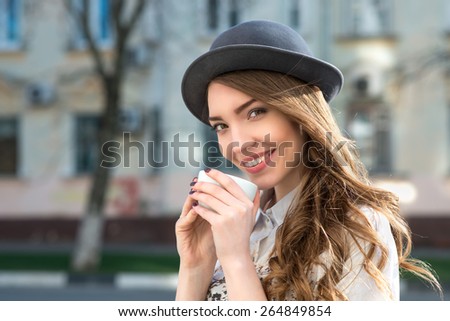 attractive woman poses with white cup. happy smile girl drink smells coffee or tea. city background
