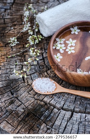 Spa and wellness setting with sea salt, flowers and towels on wooden background. Relax and treatment therapy. Manicure and pedicure settings.Selective focus. Focus on flowers in water. Close up.