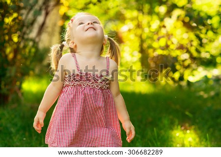 Happy smiling little girl in a meadow in the park. Facial  expression, kid and emotion.