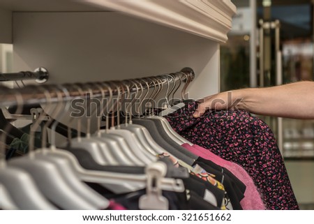 Clothes hang on a shelf in a clothes store. Close up, selective focus.