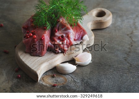 Raw lamb meat with spices on wood board over old wooden background. Close up, selective focus.
