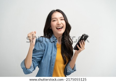 Photo of Happy Asian woman holding a smartphone and winning the prize.
