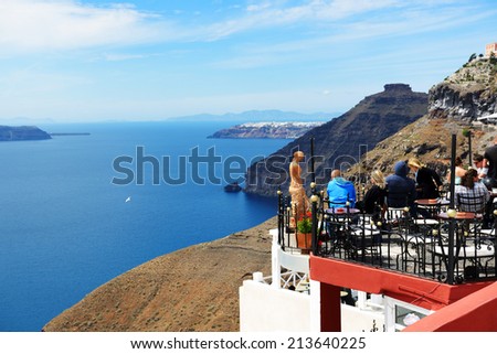 FIRA, GREECE - MAY 17: The view on Fira town and tourists enjoying their vacation on May 17, 2014 in Fira, Greece. Up to 16 mln tourists is expected to visit Greece in year 2014.