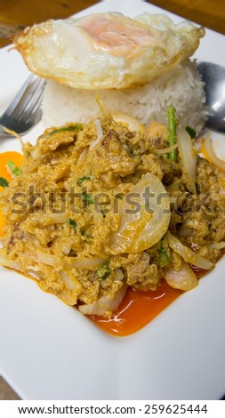 Thai style stir fried crispy pork with curry powder and sunny-side up fried egg