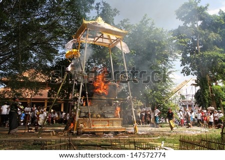 DENPASAR, INDONESIA - MAY 12:  A white bull sarcophagus burning with local village people watching during a Balinese Ngaben or cremation ceremony in Ubud, Denpasar, Bali, Indonesia on May 12, 2013.