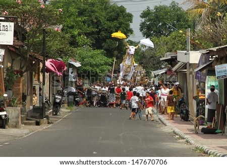 DENPASAR, INDONESIA - MAY 12: A man made white bull sarcophagus being paraded down a street to  a Balinese Ngaben or cremation ceremony in Ubud, Denpasar, Bali, Indonesia on May 12, 2013.