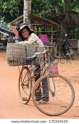 SIEM REAP, CAMBODIA - NOVEMBER 23: A Cambodian woman and her bicycle with large basket a local market near Siem Reap, Cambodia on the 23rd November, 2013.
