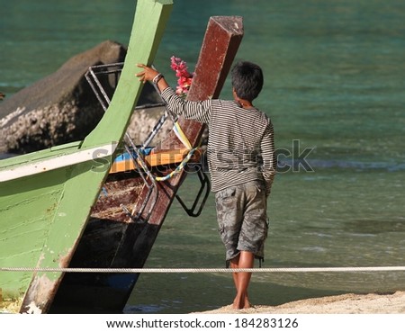 PHANG NGA, THAILAND - MARCH 11: The back view of a Moken Sea Gypsy standing by a traditional long tail boat at Mu Ko Surin National Park, Phang Nga, Thailand on the 11th March, 2014.