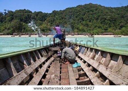 PHANG NGA, THAILAND - MARCH 11: Young Moken Sea Gypsies driving a long tail boat, fixing and bailing water out at the Surin Islands, Phang Nga, Thailand on the 11th March, 2014.