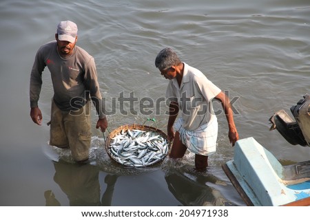 COLOMBO, SRI LANKA - MARCH 1: Two fishermen carrying a basket of fish in the lagoon near the fish markets of Negombo, near Colombo, Sri Lanka on the 1st March, 2014.