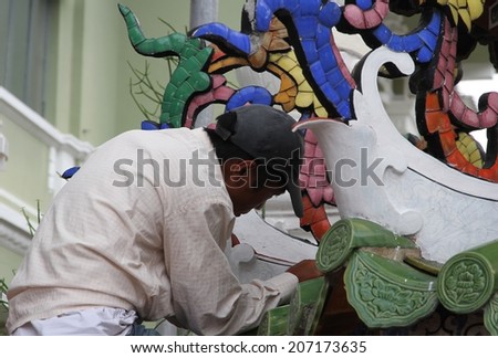 GEORGE TOWN, MALAYSIA - MAY 30: A local Malay artisan painting an ornate sculpture outside a temple in George Town, Malaysia on the 30th May, 2014.