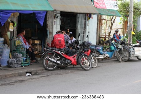KANCHANABURI, THAILAND - SEPTEMBER 3: Local men and their motor bikes outside a shop in the town of Kanchanaburi, Thailand on the 3 September, 2014.