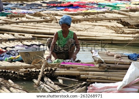 MANDALAY, MYANMAR - NOVEMBER 7:\
A woman washing clothes in the shanty town built of bamboo poles on the riverbank of the town of Mandalay, Myanmar on the 7th November 2012.