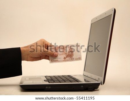 Money in hand in front of a laptop computer.