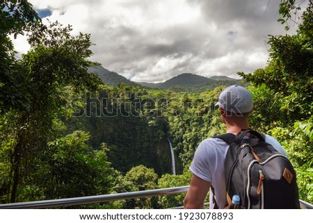Tourist looking at the La Fortuna Waterfall in Costa Rica. The waterfall is located on the Arenal River at the base of the dormant Chato volcano. Zdjęcia stock © 