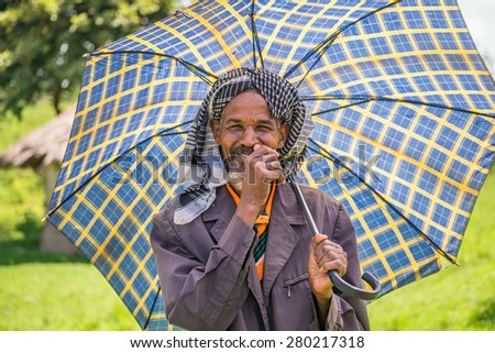 JIMMA, ETHIOPIA - MAY 2, 2015 : Old ethiopian man with an umbrella on a hot day.