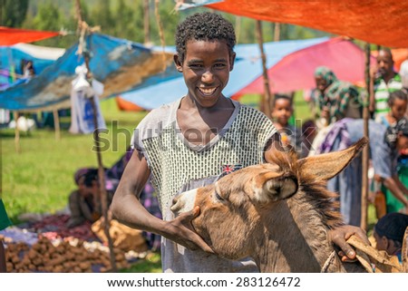 JIMMA, ETHIOPIA - MAY 2, 2015 : Young Ethiopian boy with his donkey at a popular local market in Jimma.