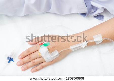 IV solution in a patient hand. Focus on asian woman\'s hand