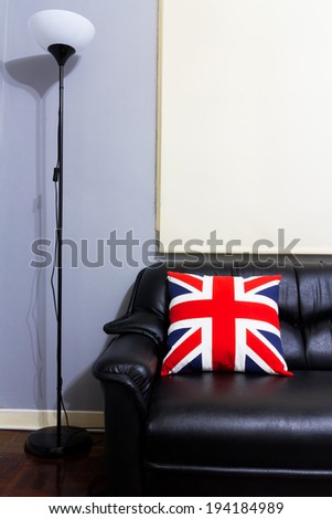 Black Leather Sofa ,union jack backrest Pillow, Floor Lamp on Wood Floor in grey room / interior concept