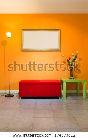 red stool chair, floor lamp, vase on green table and picture frame on orange wall