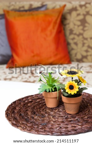 corner of cozy living room , flowers in pots on the handcraft papyrus mat and flower pattern armchair background /