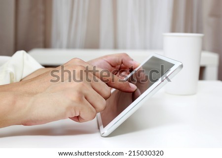 Businessman\'s hands on tablet computer, white table and white cup