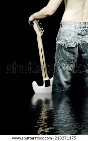 back of topless attractive man in blue jeans hold white electric guitar in his hand, standing in water & reflection / isolated on black / concept : jeans and guitar can adventure with you everywhere