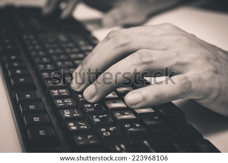 hand on Asian language computer keyboard , old B&W film processed / office syndrome for healthcare and business concept