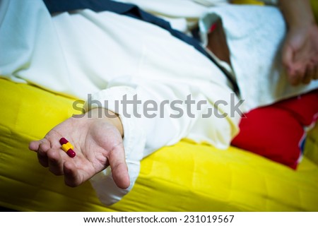 Asian drunken businessman sleep on yellow armchair with tablets & drugs in hand suffering insomnia, hangover and headache in the night