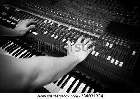 sound engineer hands on studio mixer & electric piano, synthesizer in home studio