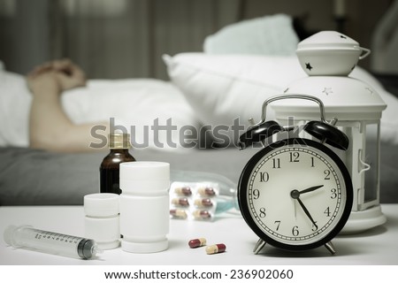 sleeping asian man in bed with tablets and drugs suffering insomnia, hangover and headache at night