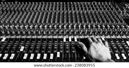 right hand of sound engineer work on recording studio mixer , black and white processed