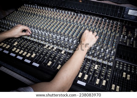 hands of sound engineer work on recording studio mixer