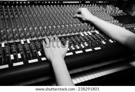 hands of sound engineer work on recording studio mixer, mixing board / black and white processed