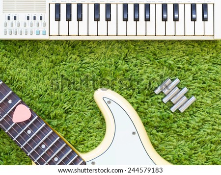 electric guitar , music keyboard / piano & pitch tuning pipe on green