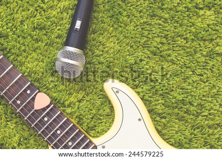 pink pick on electric guitar , dynamic microphone on green