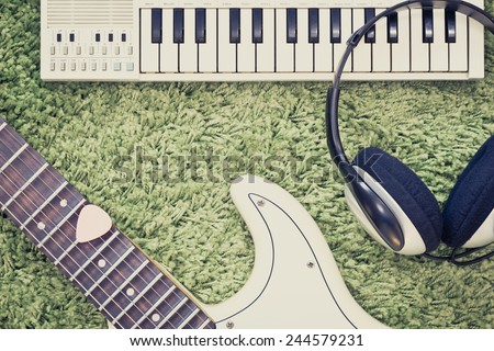 retro photo of electric guitar , headphone & music keyboard / piano on green