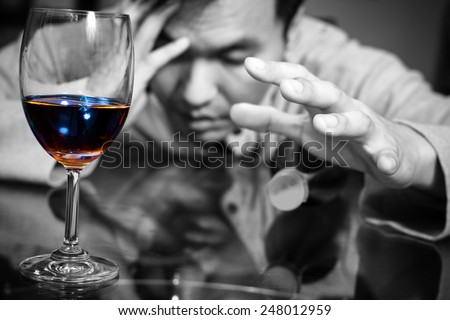 Drunk and lonely asian man & wine glass and wine, whiskey bottle / focus to glass
