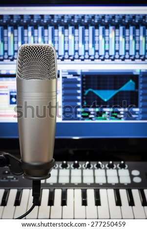 studio condenser microphone, midi keyboard synthesizer & digital mixer on screen monitor for computer music or broadcasting concept background