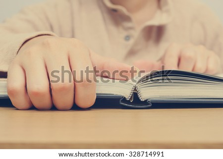 Closeup young female hand open book. shallow dept of field for reading concept background + vintage filter