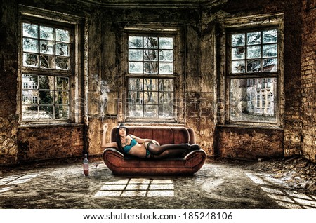 Beautiful woman is smoking on an old couch