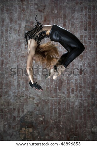 dancer makes a difficult jump  agains brick wall