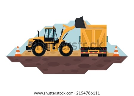 Front loader filling a dump truck with safety cones, heavy machinery used in the construction and mining industry