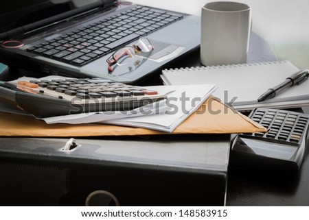 Closeup Coffee cup, laptop, Document file , pen , Calculator , notepad and glasses on wooden table