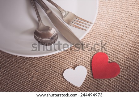 Valentines day set with silverware , white dish, hearts on sackcloth textures