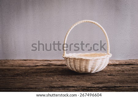 Empty wicker Basket on wooden tabletop against grunge wall. vintage tone